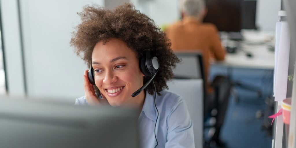 Customer experience agent smiles while helping a customer on the phone.